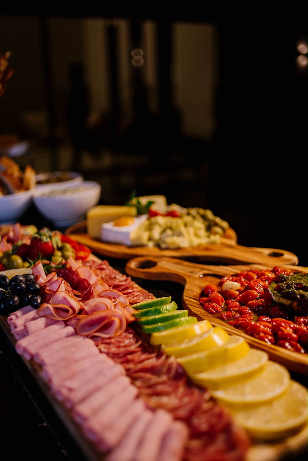 Mesa de frios com presuntos, salames, limões e queijos