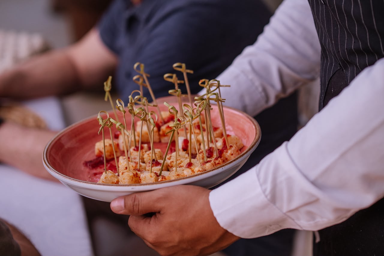 Garçom servindo canapés no palito aos convidados