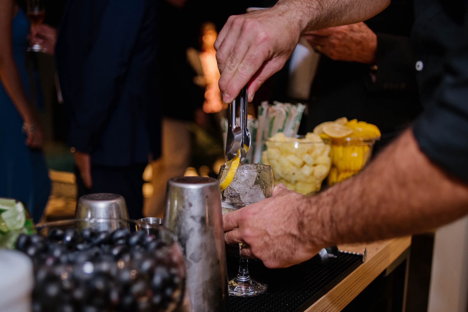 Barman preparando drinks no balcão, com frutas e coqueteleiras