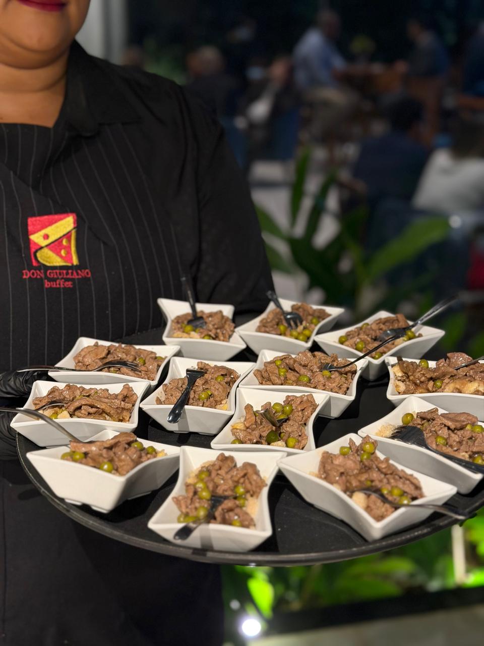 Garçom com bandeja de mini pratos de carne servidos individualmente