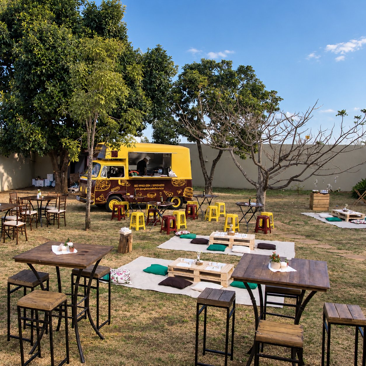 Food truck do Don Giuliano estacionado em um jardim, com mesas, banquetas e área de piquenique