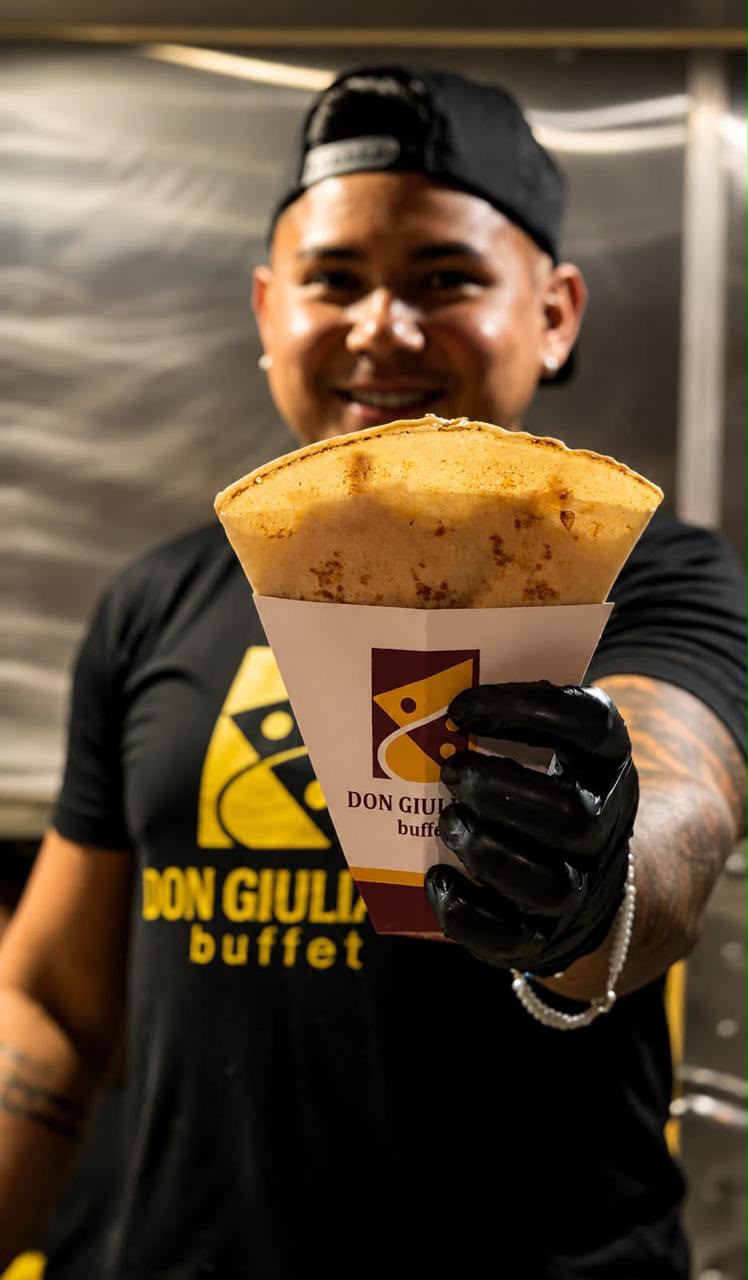 Atendente do food truck oferecendo um crepe na embalagem da marca