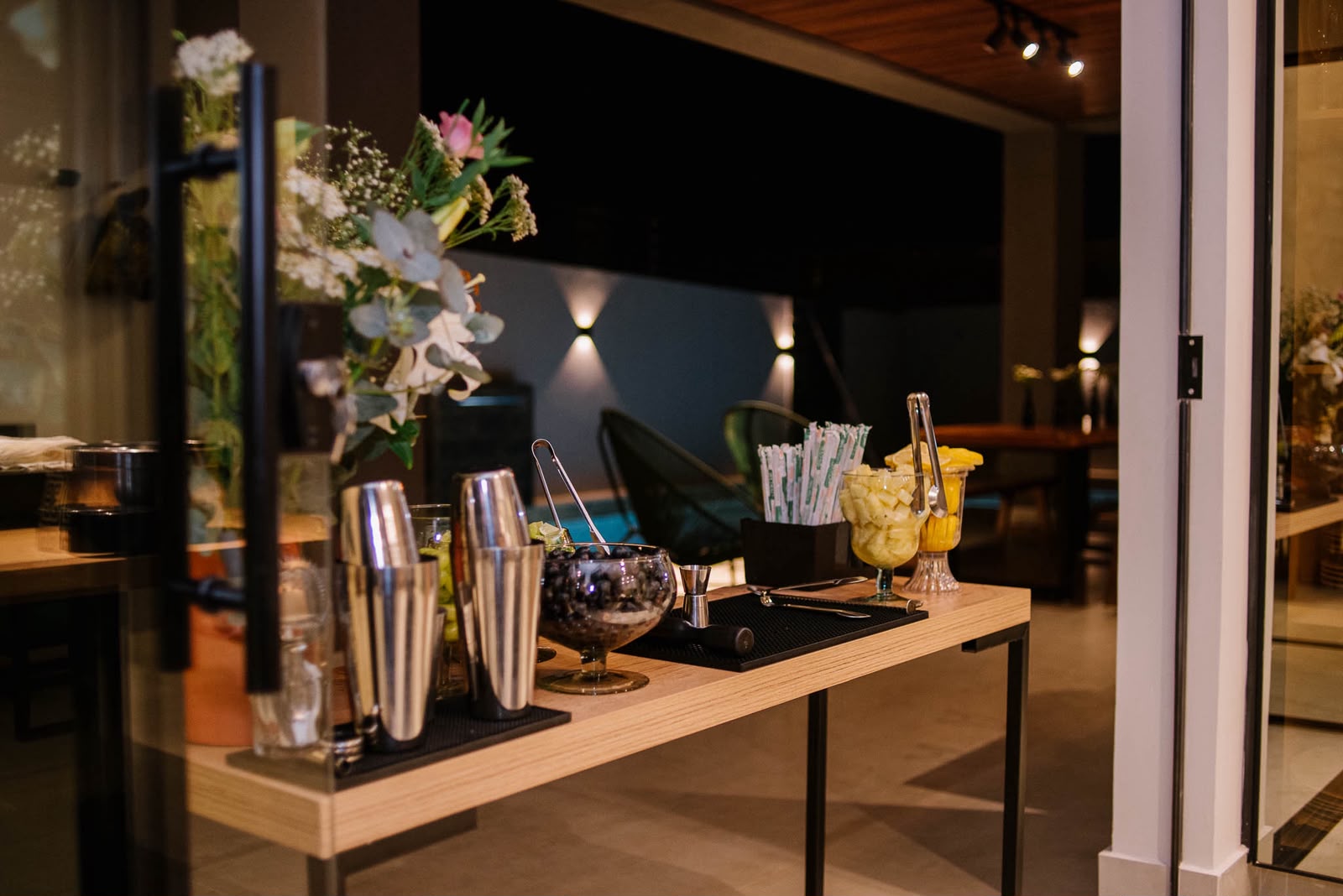 Estação de drinks montada no salão, com taças, coqueteleiras e flores